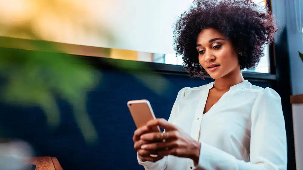 Mulher usa smartphone para interagir com Chatbot que revoluciona experi&ecirc;ncia de marca