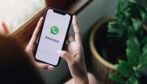 Pessoa segurando um smartphone em suas mãos, acessando o WhatsApp para empresas.