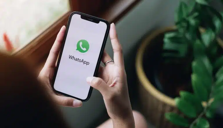 Pessoa segurando um smartphone em suas m&atilde;os, acessando o WhatsApp para empresas.