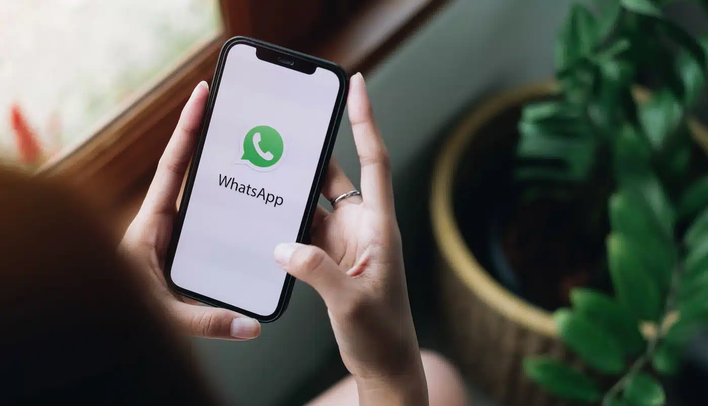 Pessoa segurando um smartphone em suas mãos, acessando o WhatsApp para empresas.