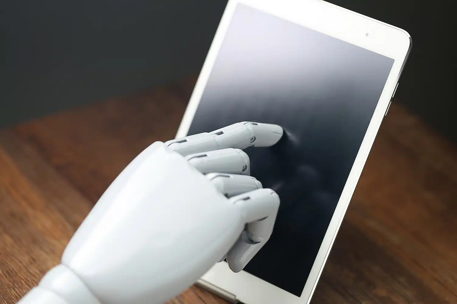 M&atilde;o rob&oacute;tica operando um tablet, representando atendimento autom&aacute;tico